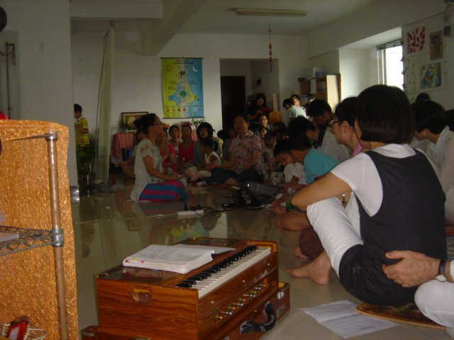 A Harmonium sits in the foreground, as Chinese people learn Sahaja Meditation